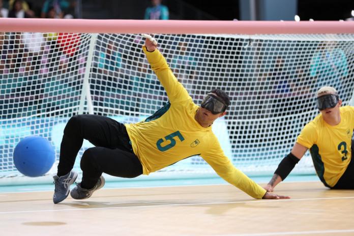 A male goalball athlete blocks a goalball
