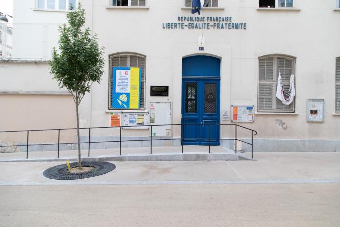 Photos shows the exterior of a municipal building. There is a slope in front of the door