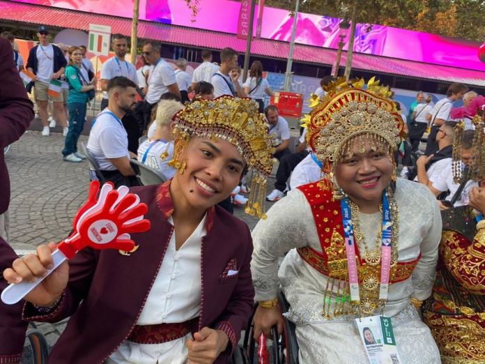 Dois atletas vestidos com trajes tradicionais posam para uma fotografia