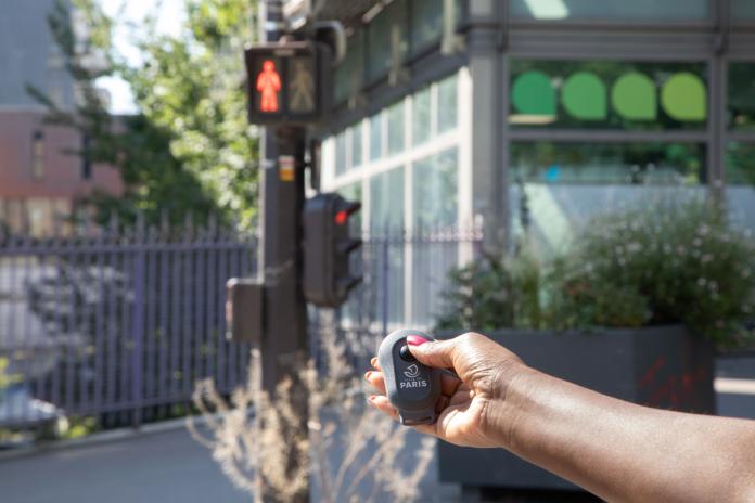 A person is holding a remote control-like device in front of a traffic light