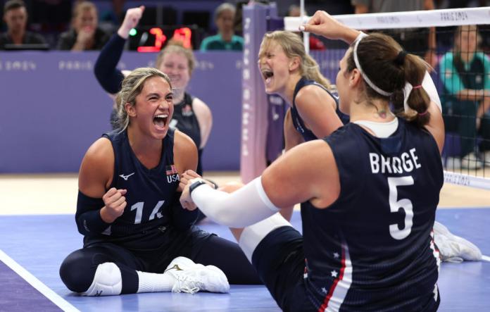 Four American women's sitting volleyball players cheer after a play