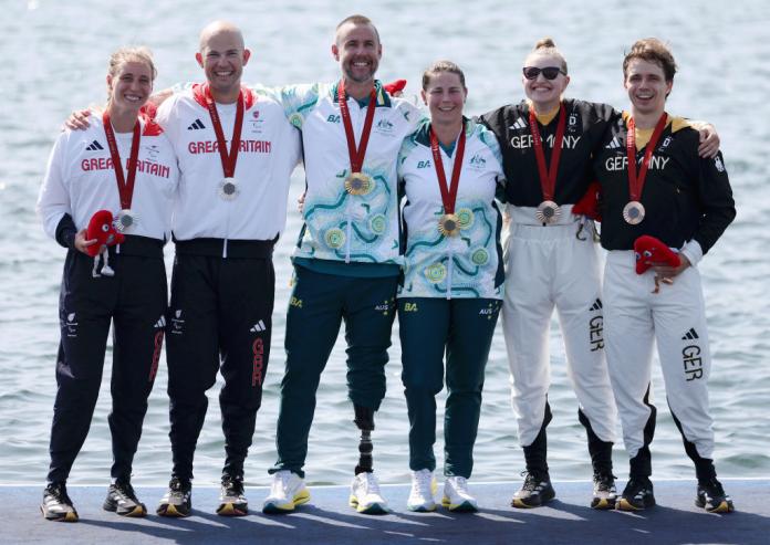 Six rowers celebrate their medals at Paris 2024 in front of the water