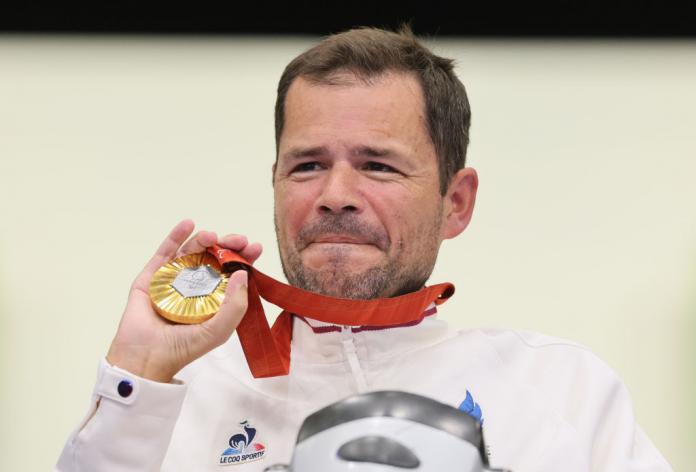 A man holds up a gold medal