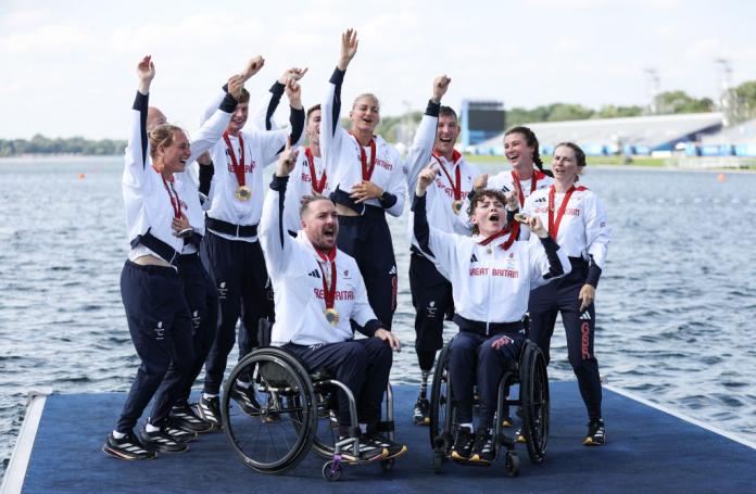 Nine people on the end of a dock wear their medals and cheer