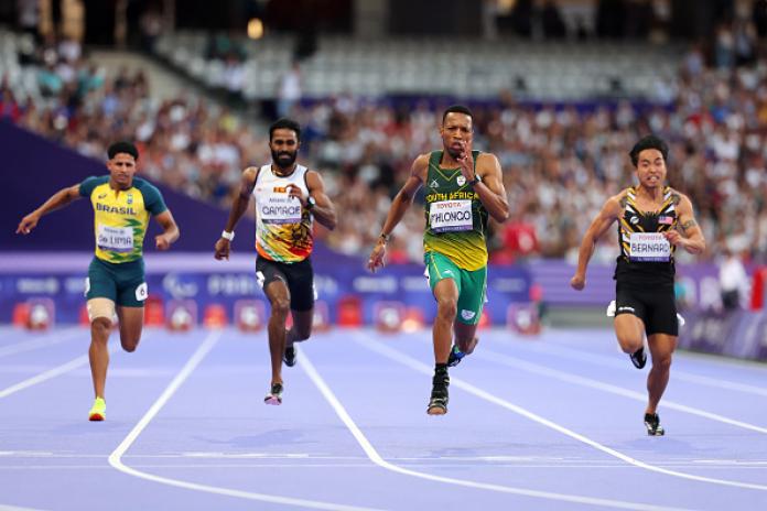Four men sprint down a purple track