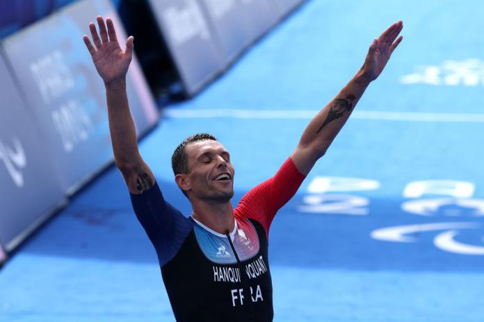 Para triathlete Alexis Hanquinquant raising his arms in celebration at the finish line