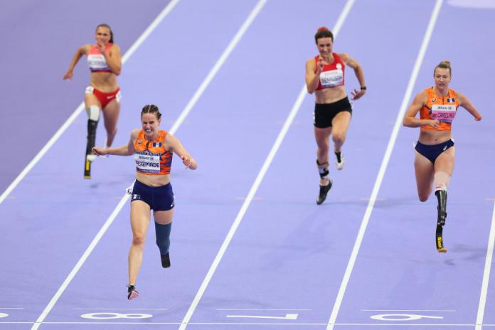 Four women sprint down a purple track.