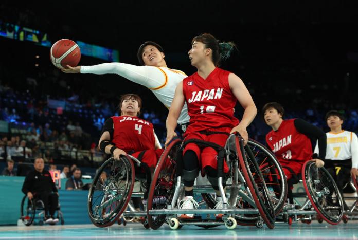 A Chinese female wheelchair basketballer reaches for the ball ahead of a Japanese player