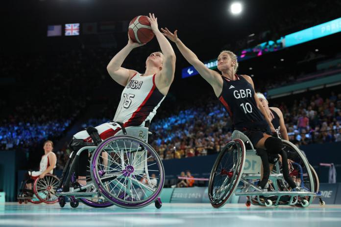 A GB female wheelchair basketballer tries to block a USA player taking a shot