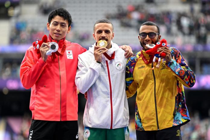 Tres hombres se paran con el uniforme de su país y se llevan las medallas a la boca como si las morderan