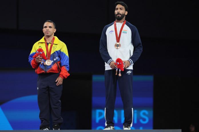 Two male Para judokas standing on a podium wearing bronze medals