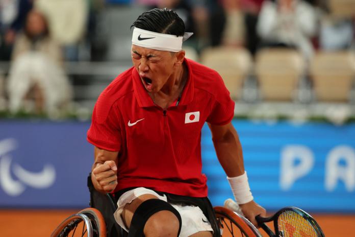 A wheelchair tennis player in a Team Japan shirt yells in reaction to a play