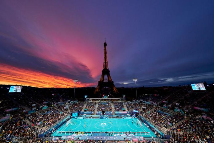 Una vista del estadio de fútbol para ciegos al aire libre de París 2024 al atardecer, con la Torre Eiffel al fondo