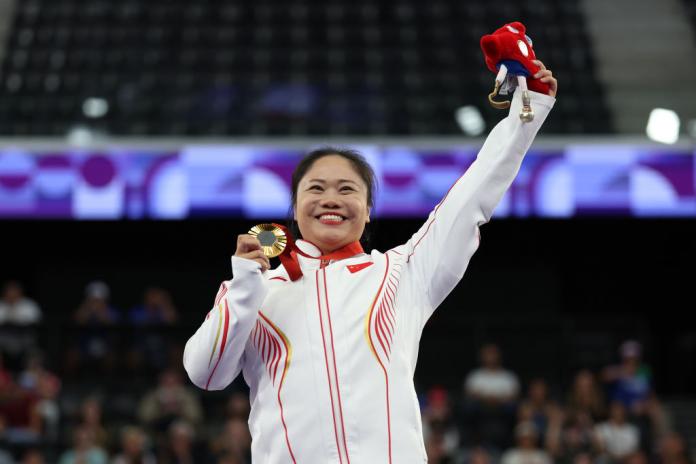 Para powerlifter Yujiao Tan holds up a gold medal and waves