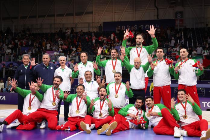 Iran's men's sitting volleyball team take a group photo wearing their gold medals and each holding up eight fingers to signify their eighth gold medal