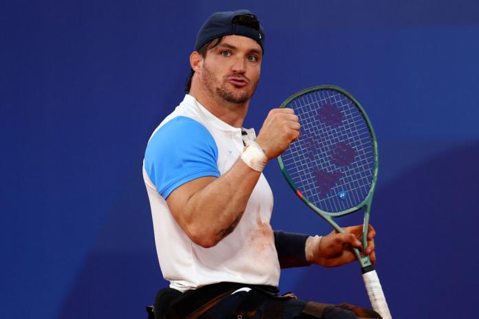 Three wheelchair tennis players smiling and chatting on the podium
