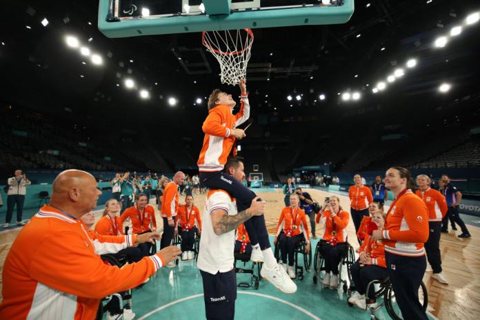 Bo Kramer sits on her coach's shoulders to cut down the basketball net