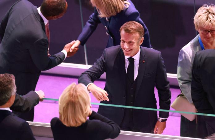 Emmanuel Macron, the French president dressed in a black suit and black tie greets guest at the Closing Ceremony