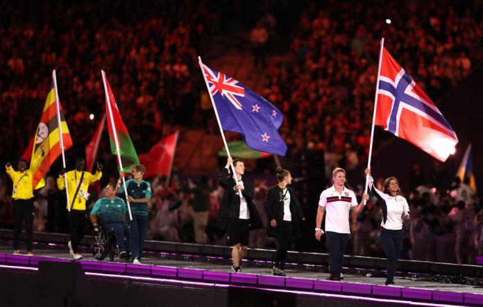 Athletes carrying several different large flags enter the Stade de France