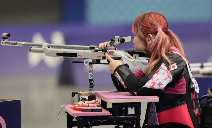 Mika Mizuta, a Japanese shooting Para sport athlete with pink hair, aims at a target