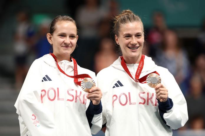 Two female Para table tennis players pose for a photo with a bronze medal