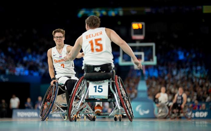 Two Dutch female wheelchair basketballers high-five on court