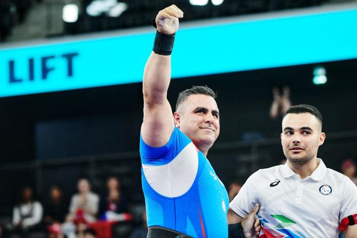 Refugee Paralympic Athlete Hadi Darvish raises his arm in a salute 