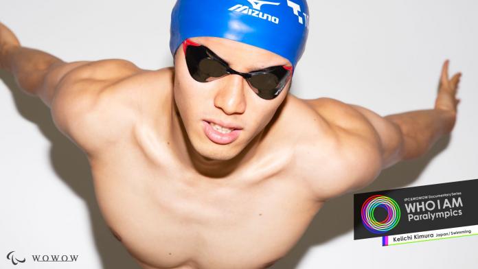 A male Para swimming athlete wearing a cap and goggles poses for a photo