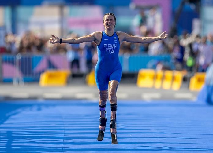 Una Para triatleta levanta los brazos durante una carrera