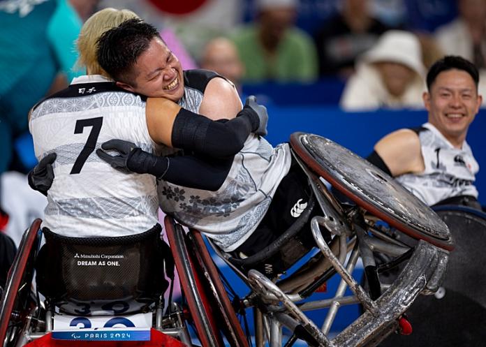 Two male wheelchair rugby players are embracing each other to celebrate victory