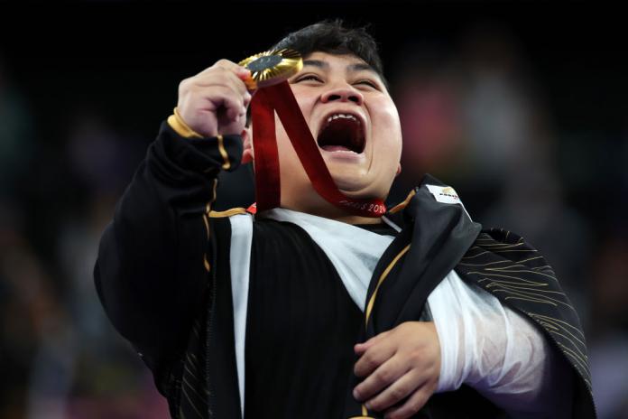 A male athlete smiles after receiving a gold medal