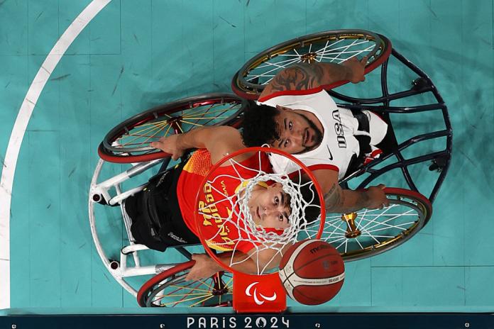 Una foto tomada desde los aros de baloncesto muestra a un hombre jugando al baloncesto en silla de ruedas