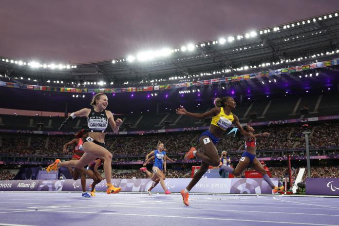 Female sprinter cross the finish line at the Paris 2024 Paralympics. The athlete in the centre is Kiara Rodriguez