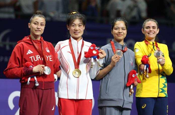 Four female athletes pose for a photo on the podium