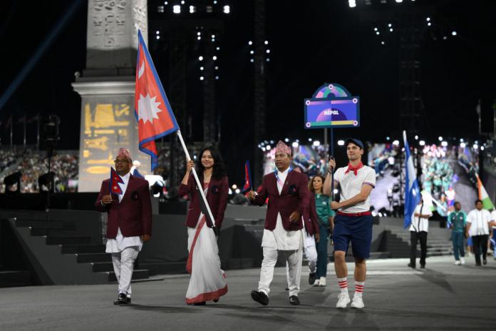A female Para athlete dressed in Nepal's traditional dress carries Nepal's flag at the Opening Ceremony of the Paris 2024 Paralympics.