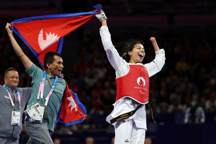 A female Para taekwondo athlete waves Nepal's flag after competing