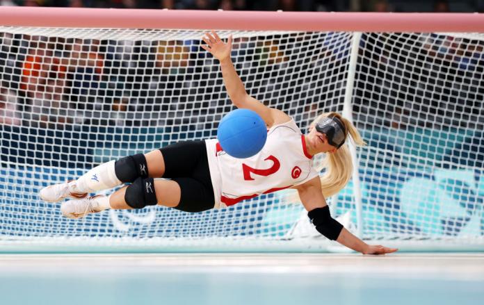 Una jugadora de goalball bloqueando el balón durante un partido.