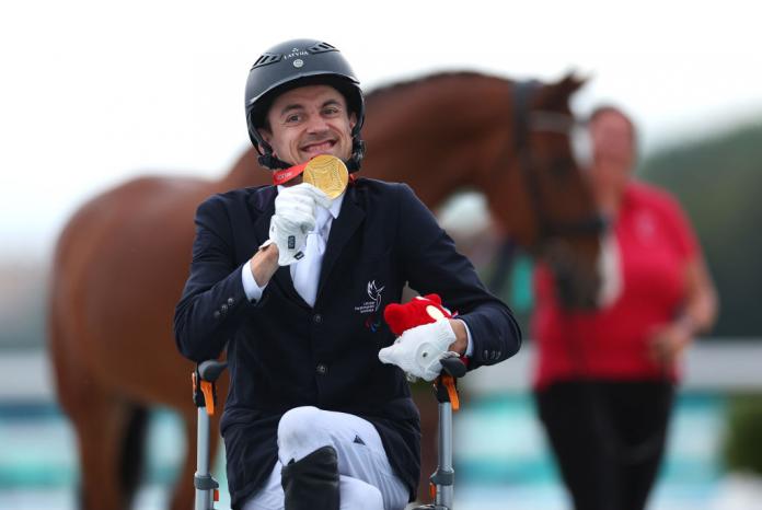 Rihards Snikus, a male Para equestrian athlete from Latvia, poses for a photo in front of his horse after receiving the gold medal