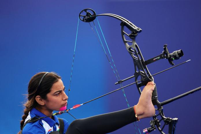 A female Para athlete prepares her bow with her right foot