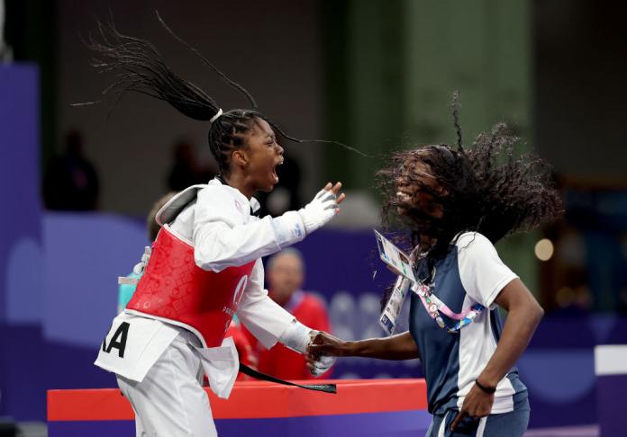 A female Para taekwondo athlete and her coach celebrates. They are both jumping