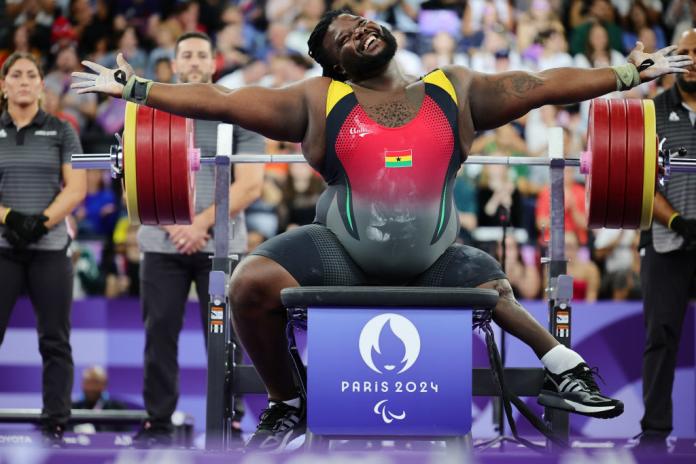 Un Para powerlifter masculino abre los brazos para celebrar un levantamiento exitoso