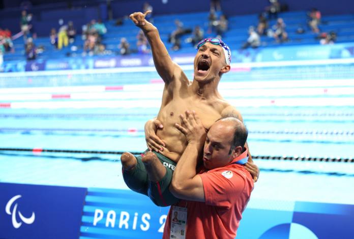 Un entrenador levanta a un atleta masculino de Para natación