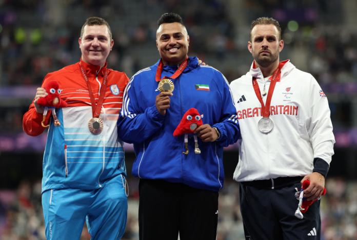 Tres atletas masculinos posan para fotos con sus medallas