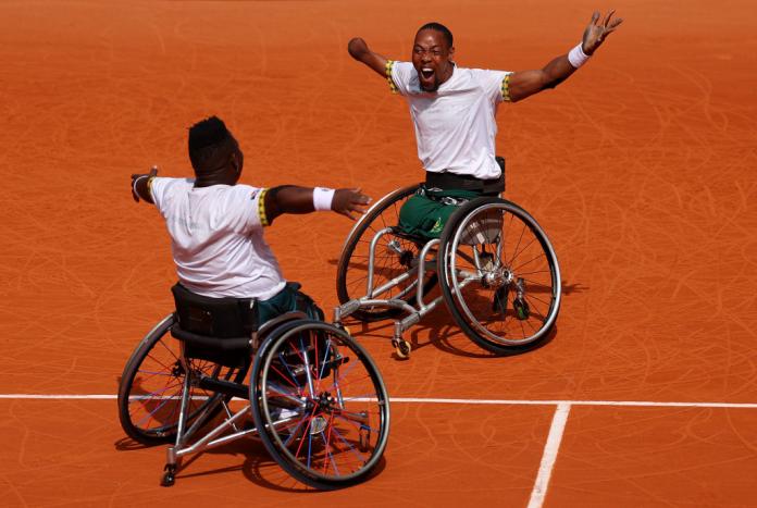 Two wheelchair tennis athletes celebrate on the tennis court