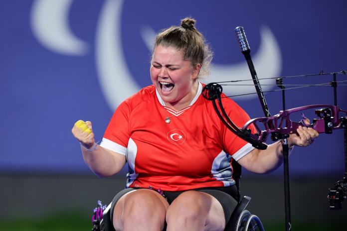A female wheelchair athlete pumps her fist in joy
