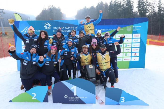 Fourteen people, including athletes and staff, pose for a photo on the podium at the Para alpine skiing world championships.