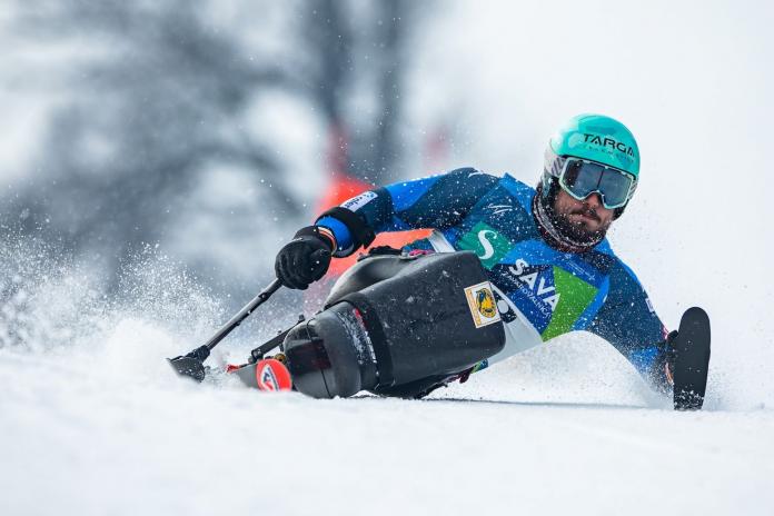 A male Para alpine sit skiing athlete in competition
