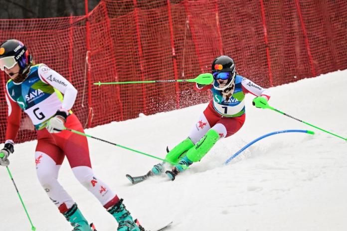 A female Para alpine skiing athlete in action, skiing behind a female guide