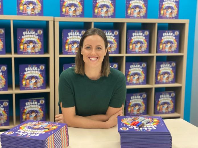 Ellie Cole posing with copies of her book during a book signing event