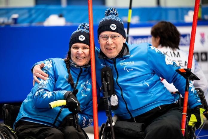 A male and female wheelchair curling athletes pose for a photo